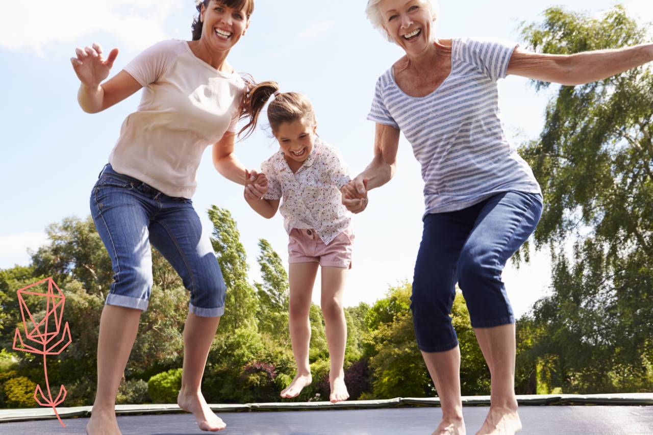 Grandmother, mother and daughter jumping on a trampoline while laughing